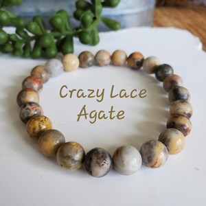 Pode incluir: Um bracelete feito de contas de &aacute;gata Crazy Lace de cor marrom, branco e amarelo.
