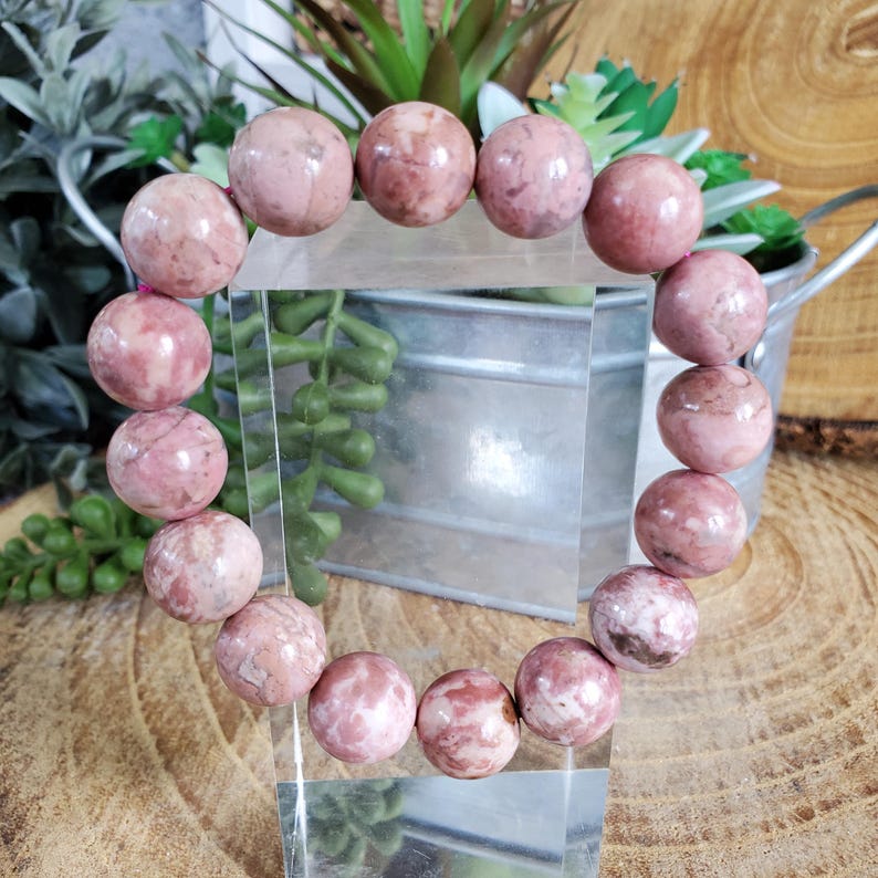 May include: A pink and white gemstone bracelet with round beads. The bracelet is made of natural stones and is a beautiful accessory for any occasion.