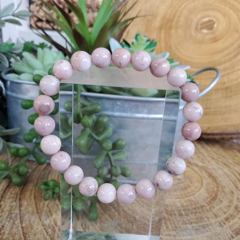 Puede incluir: Un brazalete de piedras preciosas rosa y blanco con cuentas redondas. El brazalete est&aacute; hecho de piedras naturales y es un hermoso accesorio para cualquier ocasi&oacute;n.