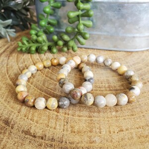 Pode incluir: Duas pulseiras feitas com contas de &aacute;gata marrom, branco e amarelo. As pulseiras est&atilde;o empilhadas uma em cima da outra.