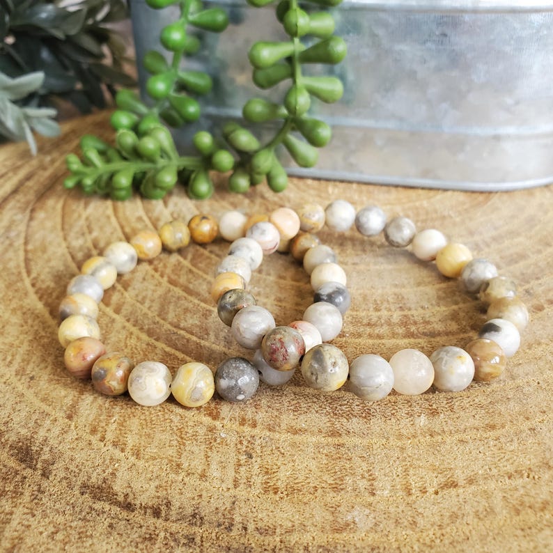 Pode incluir: Duas pulseiras feitas com contas de &aacute;gata marrom, branco e amarelo. As pulseiras est&atilde;o empilhadas uma em cima da outra.
