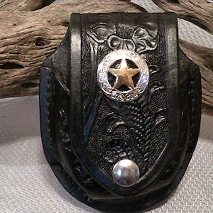 May include: A black leather pocket holster with a silver and gold star design. The holster has a snap closure and is embossed with a floral pattern.