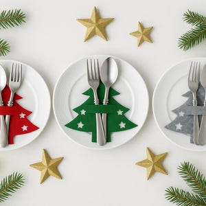 Puede incluir: Vista aérea de tres platos blancos con cubiertos y un árbol de Navidad de fieltro. Los árboles son rojos, verdes y grises, con recortes de estrellas. Estrellas doradas, velas y ramas de pino completan la decoración festiva.