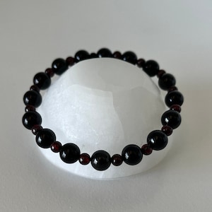 May include: A black and red beaded bracelet with alternating black and red beads.