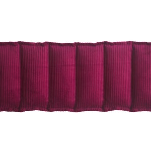 May include: A long, rectangular burgundy corduroy pillow with five sections. The pillow is filled with a soft material and is ideal for providing support and comfort.