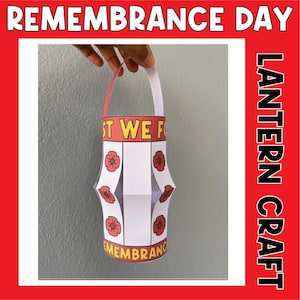 Può includere: Una lanterna di carta bianca per il Giorno del Ricordo. La lanterna è decorata con fiori di papavero rossi e il testo "Lest We Forget" e "Remembrance" in giallo.