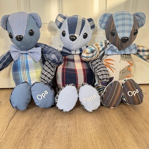 Könnte beinhalten: Drei handgefertigte Teddybären aus verschiedenen blauen, braunen und karierten Stoffstücken. Jeder Bär hat eine Fliege, schwarze Knopfaugen und auf den Füßen ist der Text Opa oder Papa in weißem Garn eingestickt.