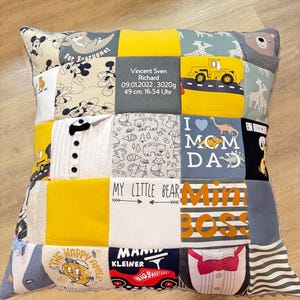 Könnte beinhalten: Ein Patchwork-Kissen mit verschiedenen Stoffquadraten. Die Quadrate zeigen Zeichentrickfiguren, Text und ein gelbes Baufahrzeug. Ein Quadrat trägt den Text "Vincent Sven Richard 09.01.2022, 3020g 49 cm. 16.54 Uhr".