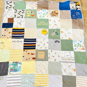 Könnte beinhalten: Eine grüne, weiße und gelbe Patchwork-Decke aus Babykleidung. Die Decke hat verschiedene Designs, darunter Tiere, ein Smiley und den Namen "Leon" mit dem Datum "31.07.2023".