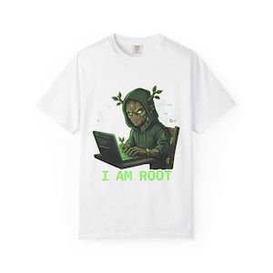Könnte beinhalten: Ein weißes Kurzarm-T-Shirt mit einer Grafik einer baumartigen Kreatur in einem grünen Kapuzenpullover, die an einem Laptop tippt. Die Kreatur hat leuchtend grüne Augen und kleine Blätter auf dem Kopf. Unter der Grafik steht der Text I AM ROOT.
