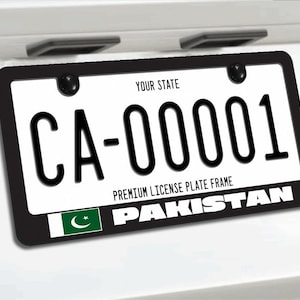 May include: A black license plate frame featuring the text "YOUR STATE" at the top, "PREMIUM LICENSE PLATE FRAME" in the center, and the word "PAKISTAN" alongside the national flag of Pakistan at the bottom, mounted on a white vehicle surface.