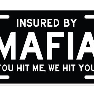 May include: A rectangular black number plate featuring white text which reads INSURED BY MAFIA and YOU HIT ME, WE HIT YOU! The plate includes four mounting slots, one in each corner, and displays a clean, bold sans-serif font across the surface.