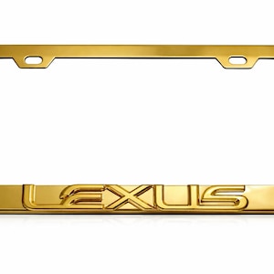 Puede incluir: Un marco de matrícula rectangular de metal color dorado con un acabado pulido y reflectante. La palabra LEXUS está grabada en letras mayúsculas en el centro de la parte inferior del marco. Tiene dos orificios de montaje en la parte superior.