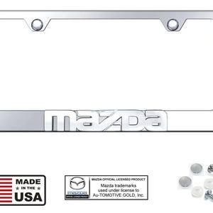 Puede incluir: Un marco cromado para matrícula Mazda con el logotipo de Mazda. Incluye accesorios de montaje. El marco es rectangular con esquinas redondeadas y tiene dos orificios de montaje. También se ve el texto "MADE IN THE USA".