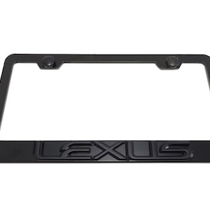 Puede incluir: Un marco de matrícula rectangular en color negro mate con la palabra LEXUS en relieve a lo largo del borde inferior. El marco incluye dos puntos de montaje circulares en la parte superior con tapas negras a juego para un acabado limpio.