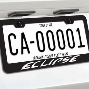 May include: Black license plate frame with a white license plate. The license plate reads "CA-00001". The frame has the word "ECLIPSE" in white. The top of the license plate frame reads "YOUR STATE" and "PREMIUM LICENSE PLATE FRAME".
