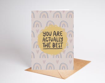 May include: A greeting card with a light pink background and a repeating pattern of rainbow arches. The card has a yellow circle with the text "You are actually the best" in black.
