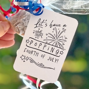 May include: White card with black text and illustrations. The text reads "Let's have a poppin' fourth of July!" with fireworks illustrations.