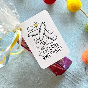 K&ouml;nnte beinhalten: Eine wei&szlig;e Karte mit einem Comic-Flugzeug und dem Text "You are plane awesome!" Die Karte ist mit einem gelben Band an eine durchsichtige Plastikt&uuml;te gebunden, die mit S&uuml;&szlig;igkeiten gef&uuml;llt ist.