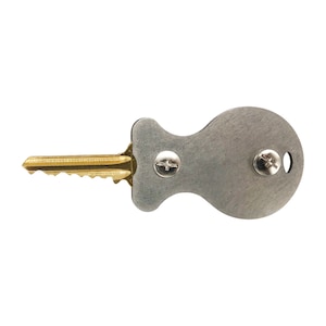 May include: A silver key with a round, flat, metal tag attached to the end. The tag has two screws on it.
