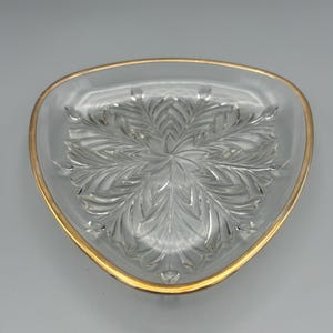 May include: A clear glass triangular dish with a gold rim and a decorative etched pattern.
