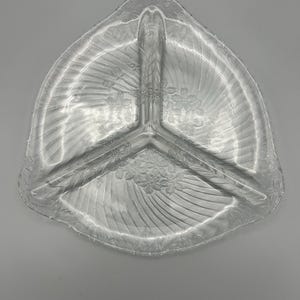 May include: A clear glass serving dish with three sections. The dish has a swirl pattern and a scalloped edge.
