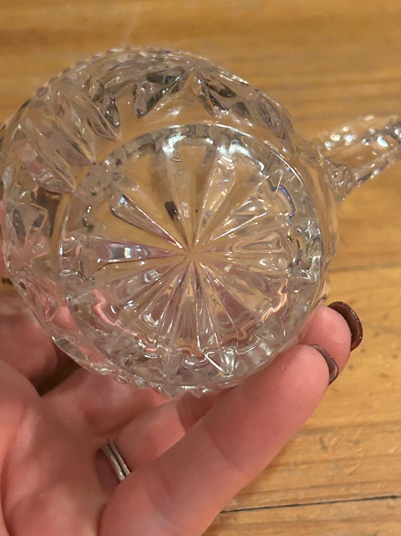 Op de afbeelding: Een glazen kan met een diamantpatroon. De kan heeft een handvat en een tuit.