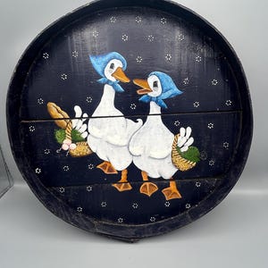 Round decorative navy blue pallet tray with pair of basket holding geese