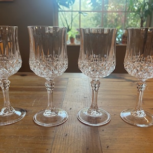 May include: Four clear glass wine glasses with a diamond pattern. The glasses have a tall, slender stem and a round bowl.