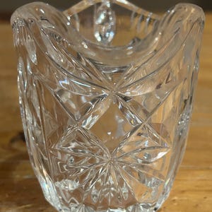 Op de afbeelding: Een glazen suikerpot van helder glas met een geslepen glasontwerp. De pot heeft een ronde vorm en een brede opening.