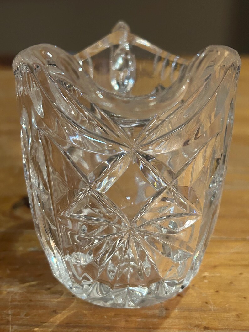 Op de afbeelding: Een glazen suikerpot van helder glas met een geslepen glasontwerp. De pot heeft een ronde vorm en een brede opening.