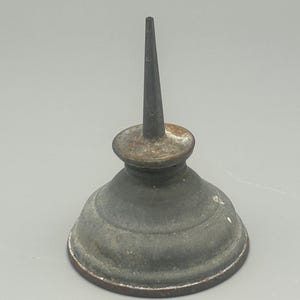 May include: A vintage, antique oil can with a conical spout and a rounded base. The can is made of metal with a weathered, aged appearance, showing signs of rust and wear. The spout is long and slender, designed for precision oiling.