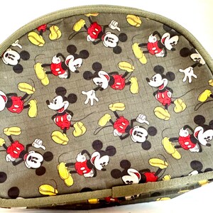 May include: A half-moon shaped bag with a repeating pattern of Mickey Mouse in red shorts, yellow shoes, and white gloves on a gray background. The bag has a green trim and a zipper closure.