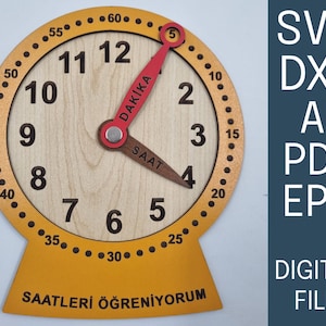 May include: Wooden educational clock with a light wood face, yellow and brown accents, and red clock hands. The clock face displays numbers and minute markers. Text on the clock face reads "DAKIKA" and "SAAT". The base of the clock has the text "SAATLERİ ÖĞRENİYORUM".