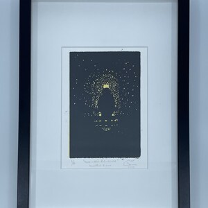 Pode incluir: Uma impressão em preto e branco de uma pessoa em pé em um campo de estrelas. A impressão é emoldurada em uma moldura preta e tem o texto "more-less has-ever" e "Meredith & Kim" escrito nela.