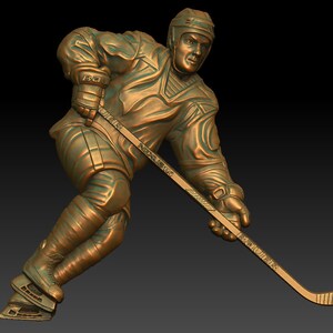 Puede incluir: Una escultura de bronce de un jugador de hockey en acción, sosteniendo un palo de hockey con la palabra "Bauer" en él. El jugador lleva un casco y patines.
