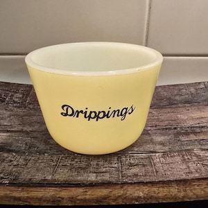 May include: A yellow ceramic dish with the word "Drippings" printed in black lettering.