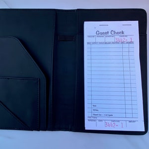 May include: Black leather check presenter with a white guest check inside. The check has the words "Guest Check" printed at the top and the check number "3442-1" written in red ink.