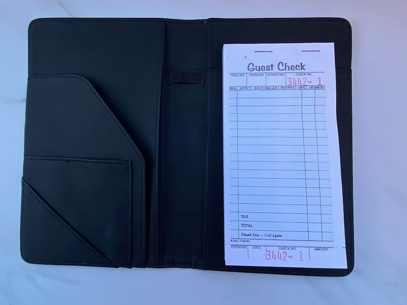 May include: Black leather check presenter with a white guest check inside. The check has the words "Guest Check" printed at the top and the check number "3442-1" written in red ink.
