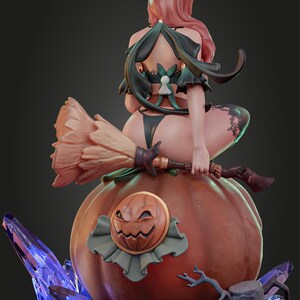 Puede incluir: Una figura de bruja con cabello rosado, vestida con un atuendo de bruja negro y verde, se sienta sobre una gran calabaza naranja con una cara de calabaza tallada. La bruja sostiene una escoba en su mano y est&aacute; rodeada de objetos azules que parecen cristales.