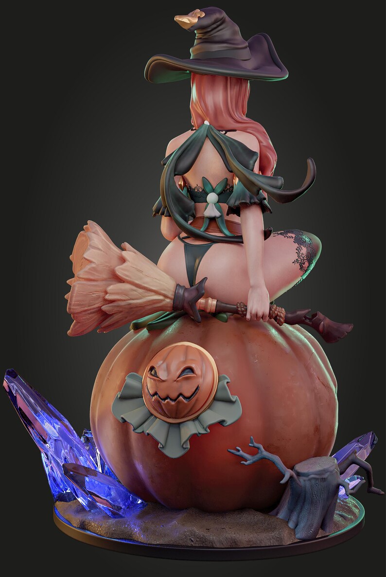 Puede incluir: Una figura de bruja con cabello rosado, vestida con un atuendo de bruja negro y verde, se sienta sobre una gran calabaza naranja con una cara de calabaza tallada. La bruja sostiene una escoba en su mano y est&aacute; rodeada de objetos azules que parecen cristales.