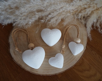 Peut inclure: Quatre ornements en forme de cœur blancs avec une surface texturée en grille. Deux des cœurs sont dotés de boucles en ficelle de jute et de petites perles en bois pour les suspendre, tandis que les deux autres sont sans attaches.