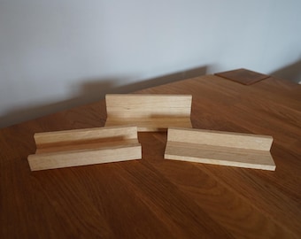 Peut inclure: Trois présentoirs en bois, chacun avec une forme et une taille différentes, sont disposés sur une table en bois. Les présentoirs sont en bois brun clair et ont une finition naturelle.