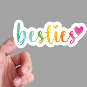 May include: A rainbow watercolor sticker with the word "besties" and two small hearts.