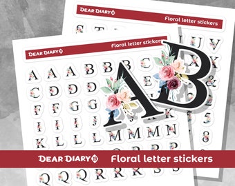 Op de afbeelding: Een vel met alfabetstickers met bloemenontwerpen. De stickers zijn wit met zwarte letters en bloemenillustraties in roze, blauwe en groene tinten. Op het vel staat de tekst "DEAR DIARY" en "Floral letter stickers".