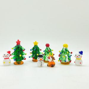 May include: A set of miniature glass Christmas ornaments, including a reindeer, snowmen, and Christmas trees with colorful lights and star toppers.
