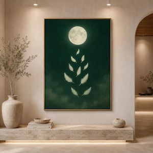 Könnte beinhalten: Ein gerahmter Kunstdruck mit einem Vollmond und einer Reihe von absteigenden Federn vor einem dunkelgrünen Hintergrund. Das Kunstwerk hat einen goldenen Rahmen und wird in einem gut beleuchteten Raum mit neutralen Tönen ausgestellt. Das Thema ist himmlisch und ätherisch.
