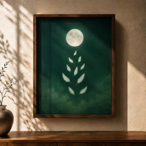 Könnte beinhalten: Ein gerahmter Kunstdruck mit einem dunkelwaldgrünen Hintergrund und einem hellen Vollmond in der oberen Mitte. Unter dem Mond ist eine vertikale Anordnung von neun weißen Federn in einem symmetrischen Muster vor dem dunklen Hintergrund dargestellt.