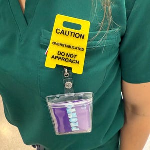 Precaución: Sobreestimulación en el carrete de insignias - Señal amarilla con texto negro, mensaje de advertencia para concienciar sobre la seguridad