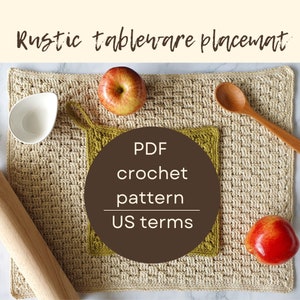 May include: A crocheted placemat in a beige colour with a green crocheted square on top. The text "PDF crochet pattern US terms" is on a brown circle in the centre of the image. There are two red apples and a wooden spoon on the placemat.